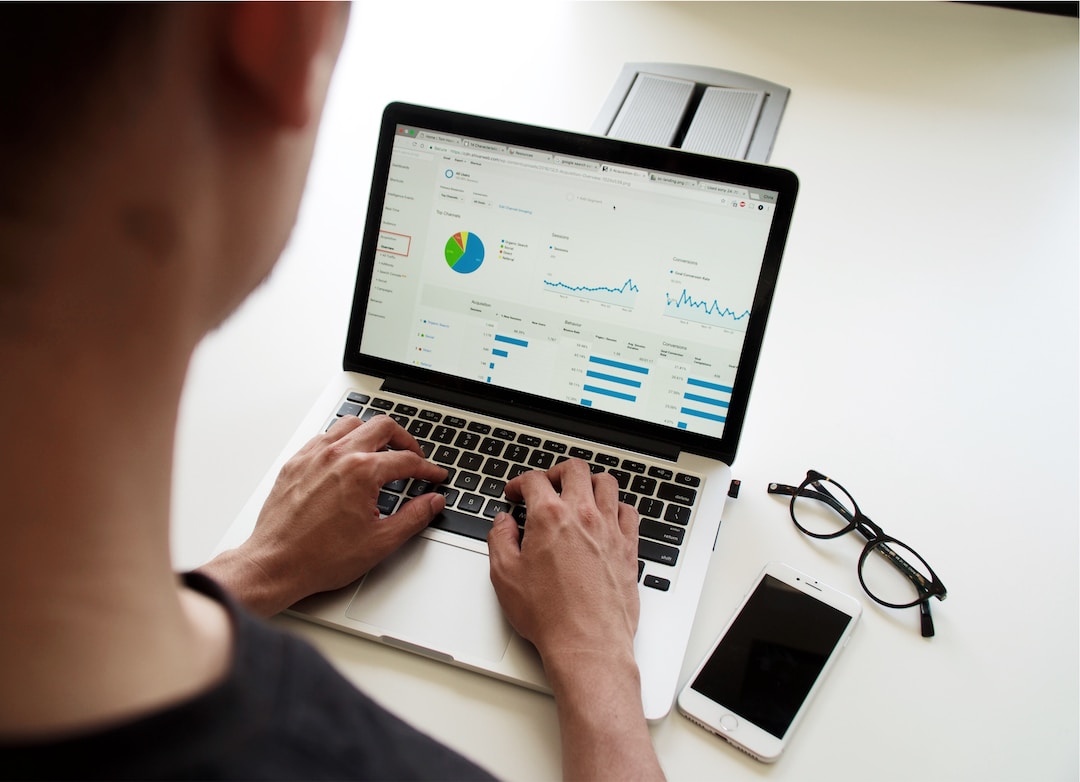 A person on a laptop creating a dashboard showing the different types of charts, with glasses and a phone beside them.