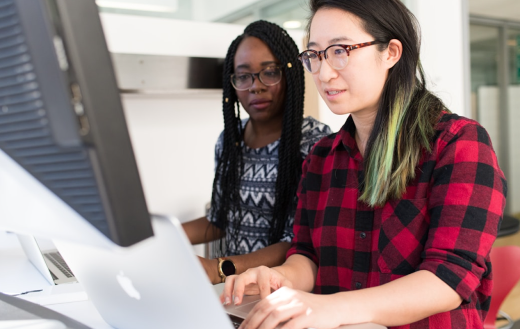 Two female employees utilizing an account management tool on a computer to streamline the financial processes of their business